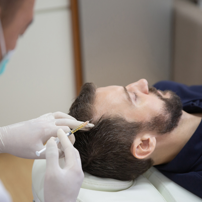Plasma rico en plaquetas Hombre tumbado al que un profesional le inyecta Algún tipo de sustancia en la zona posterior d la cabeza por encima de la sien